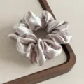 Nahaufnahme Detail von Strass Satin Haargummi, elegantes gerafftes Design für Damen Zöpfe. - Champagner