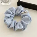 Detailopname van lichtblauwe satijnen haarring, glanzende stof met handgemaakt stoffen label. - Blauw