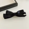 Detailansicht der schwarzen Satin Schleife Bananen Haarklammer mit eleganter Plakette. - Reguläre Passform / Schwarz