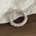 Nahaufnahme des satin Haargummis mit Kristallen zur Detailansicht der feinen Textur. - Aprikose