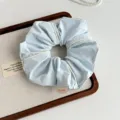 Light blue fabric hair scrunchie with white piping detail, elegant hair accessory close up. - Blue