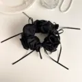Detailed view of black lettuce edge hair scrunchie with bow ribbon and elegant pearl charm. - Black