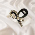 Close-up detail of a chic black hair claw clip adorned with sparkling rhinestones and white flowers. - Black Ribbon Bow Claw Clip
