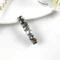 Detailed shot of sparkling rhinestone and pearl decorative hair clip on white surface background - Type A Grey Velvet