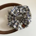 Vue détaillée d'un chouchou en tissu à carreaux vintage, avec texture douce et perles élégantes. - Chouchou