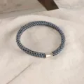 Dark grey woven hair tie with gold metal tube detail, high elasticity and durable daily wear. - Blue