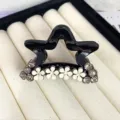 Detailed view of the chic black star hair claw clip accented with rhinestones and white flowers. - Star Shape Style / Black