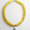 Gedetailleerde close-up van de gele kralenketting met een prachtige parelhanger detail. - Halskettingen met transparante gele parels
