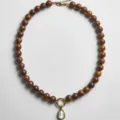 Handgemaakte kralenketting met druppelvormige kristallen hanger en bruine ronde kralen. - Kettingen met bruine druppelstrass