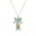 Close-up detail van de maart geboortebloem narcis strik ketting hanger in roestvrij staal. - Kettingen met geboortebloemkaart voor maart