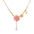 Gedetailleerde close-up van vergulde bloemhanger ketting met roze emaillering en parels. - Oktober Geboortebloem
