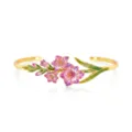 Close-up detail of gold-plated open cuff bracelet with pink enamel floral design and green leaves. - Purple Iris