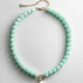 Detailopname van mintgroene kralenketting met gouden kettingverlenging en ringhanger. - Kettingen met lichtcyaan parels