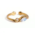 Primer plano detallado de un elegante anillo abierto dorado con diseño de doble piedra de cristal. - Anillo de Junio