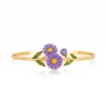 Close-up of gold-plated stainless steel open cuff bracelet with purple enamel daisy and green leaves. - Purple Daisy Flower