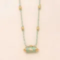 Detailed shot of turquoise braided cord necklace featuring prayer wheel bull pendant and gold beads. - Cow