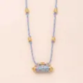 Detailed shot of the gold-plated dolphin cylinder pendant and purple braided rope. - Whale