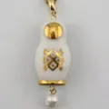 Λεπτομερής κοντινή λήψη του vintage μενταγιόν ρωσικής κούκλας με χρυσό και μαργαριτάρι. - Κολιέ ματριόσκα με λευκό καρό