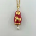 Gros plan d'un collier poupée russe rouge vintage avec cheval doré et perle. - Colliers matriochka cheval rouge
