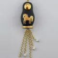 Détail en gros plan du pendentif poupée russe rétro avec motif de cheval doré et chaînes pendantes. - Colliers matriochka cheval noir dorés