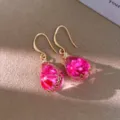 Close-up detail of resin flower teardrop earrings with gold hooks and pink dried blooms. - Gold-Pink Hook Style / Pink