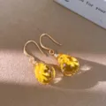 Close-up of golden teardrop resin earrings featuring delicate yellow dried flowers inside. - Gold Hook - Yellow / Yellow