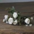 Close-up detail shot of vintage artificial white rose bouquet with green eucalyptus leaves. - White