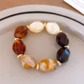 Close-up detail shot of chunky geometric acrylic resin beaded bracelet in amber and cream tones. - Bracelet / Brown