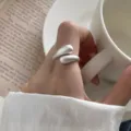 Gedetailleerde close-up van een minimalistische zilveren open druppelring op de hand. - Verstelbaar Open / Stroomlijnde Waterdruppel Stijl (K102K)