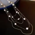 Elegant multi-strand pearl necklace, gold tone chain, stylish sweater accessory detail shot. - Necklace - Gold - White
