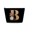 Close-up of black cosmetic pouch with gold letter B and floral print, portable zip bag. - Capital Letter B Style