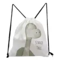 Close-up detail of the cute cartoon dinosaur canvas drawstring backpack with black straps. - Green Dinosaur Pattern (sk3061)