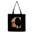 Black canvas tote bag detail featuring elegant gold letter C and vintage floral print design. - Letter C Print (hm3191)
