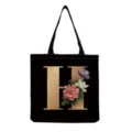 Black canvas tote bag featuring a gold floral monogram letter H design for daily shopping use. - Letter H Print (hm3201)