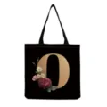 Black canvas tote bag featuring a golden letter O and vintage floral print design details. - Letter O Print (hm3393)