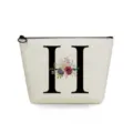 Close-up detail of the canvas cosmetic makeup pouch featuring floral letter print and zipper. - Letter H Style