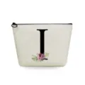 Detail view of a beige linen makeup pouch featuring a black letter I and floral print. - Letter I Style