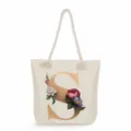 Detailed view of a beige canvas tote bag featuring a gold letter S and elegant floral print. - Golden Letter S Print Style