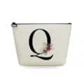 Close-up detail of white canvas cosmetic pouch with elegant black letter Q and floral art. - Letter Q Style