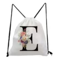 Detailed close-up of the white drawstring bag showcasing the elegant floral letter E print. - Letter E Style