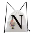 Close-up detail of the white drawstring backpack featuring a black letter N and floral print. - Letter N Style