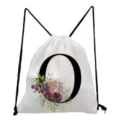 Close-up detail of white canvas drawstring backpack featuring black letter O and floral print. - Letter O Style