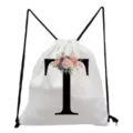 Close-up detail of white drawstring backpack featuring floral letter T print and black cords. - Letter T Style