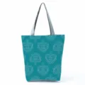 Close-up detail of the teal tote bag featuring a unique white geometric eye pattern design. - Geometric Eye Heart (hl2711)