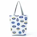 Close-up of the stylish evil eye patterned canvas tote bag with durable grey shoulder handles. - Classic Blue Gold Evil Eye (hl2721)