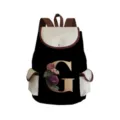 Canvas floral letter G backpack detail showing black bag with cream flap and elegant flower print. - Black Letter G Style