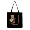 Detail view of a black canvas tote bag featuring an elegant gold letter U with vintage floral print. - Letter U Print (hm3396)