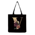 Close-up of black canvas tote bag featuring elegant gold letter V and vintage floral graphic. - Letter V Print (hm3187)