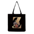 Close-up detail of the black canvas tote bag featuring gold letter Z and vintage floral print. - Letter Z Print (hm3255)
