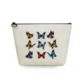 Vista en detalle del neceser de lona con estampados de mariposas de colores y cremallera negra. - Nueve Mariposas